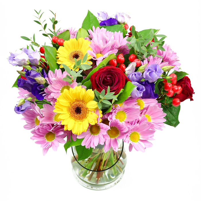 In this image, a lavish mixed bouquet bursts from a simple clear glass vase, the entire composition captured against a clean white background that highlights every nuance of colour and shape. At the core, sumptuous deep red roses spiral outwards, their plush petals exuding a sense of classic romance and warmth. Nestled alongside them, two radiant yellow gerbera daisies with dark brown-orange centres beam with cheerful energy, providing a sunny counterpoint to the roses' intensity. Encircling these key blooms is a generous ring of soft pink and pale lilac chrysanthemums or daisies, their many fine petals arranged around golden centres, giving the arrangement extra volume and a gentle, comforting softness. Slender stems of lisianthus in shades of purple and lavender weave through the bouquet, their bell-like flowers and unopened buds adding elegant height and a cool, sophisticated tone that balances the brighter hues. Scattered among the petals, clusters of smooth red hypericum berries sit like tiny marbles, creating pockets of texture and a subtly festive feeling. Layers of greenery in different tones-from deep forest-green leaves to lighter, more feathery sprigs-cradle the flowers and give the design an organic, garden-inspired structure, reminiscent of the lush planting around Barnsbury Square. The clear vase reveals the neatly cut stems submerged in fresh water, underscoring the care and precision behind the arrangement. Overall, the bouquet feels joyful, generous, and thoughtfully composed, perfect for marking milestones, saying thank you, or bringing a splash of colour into a Barnsbury living room bathed in soft afternoon light. It's the kind of design a trusted local studio like Flower Delivery Barnsbury would prepare for same-day delivery in the neighbourhood.